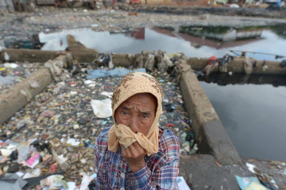 Une mère de famille indonésienne devant un barrage rempli d’ordures à Jakarta, en 2013. 