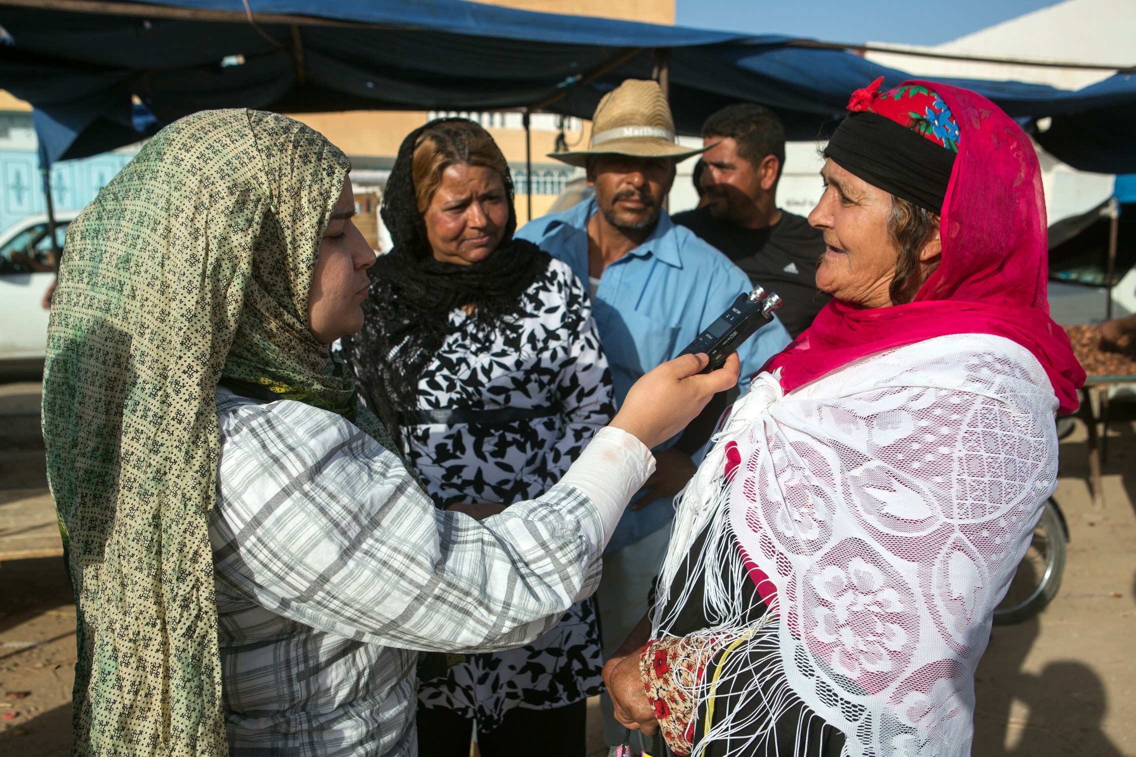 Une correspondante de la radio Gafsa à Kasserine, interview une femme sur le marché de Kasserine, une ville de Tunisie située à environ 300 km au sud de Tunis, le 15 juin 2015. © Fondation Hirondelle / Gwenn Dubourthoumieu